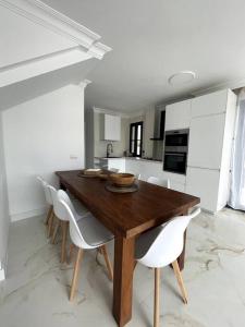 a kitchen with a wooden table and white chairs at Sunset of Duke#Luxury Costa Adeje in Adeje