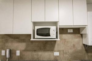 a microwave in a kitchen with white cabinets at Moderno Dpto en zona de bodegas in Ciudad Lujan de Cuyo