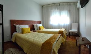 a hotel room with two beds and a window at Casa Valadim in Chaves