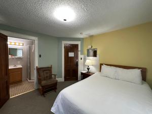 a bedroom with a white bed and a chair at The Colonial Inn & Creamery in Watkins Glen