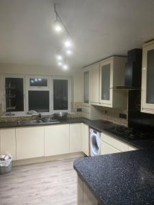 a kitchen with white cabinets and a black counter top at LA Mansion in Wednesbury