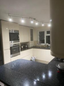 cocina con armarios blancos y encimera negra en LA Mansion en Wednesbury