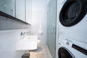 a bathroom with a sink and a washing machine at Eggie's Nest - Luxury City Apartment in Sydney +83 photos