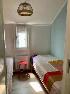 Un pequeño dormitorio con 2 camas y un taburete rojo en Daalders Plakkie, en Elahuizen