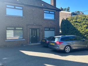 two cars parked in front of a brick house at Belfast Macs double room shared bathroom in Belfast