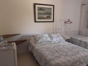 um quarto com uma cama e uma fotografia na parede em Recanto Suítes em Araruama