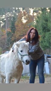 una mujer parada junto a un caballo blanco en Gajówka Świt, 