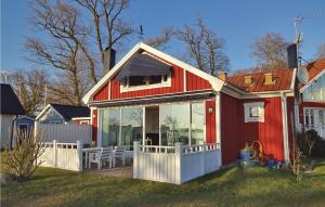 une petite maison rouge avec une terrasse et des portes en verre dans l'établissement Awesome Home In Slvesborg With House Sea View, à Sölvesborg