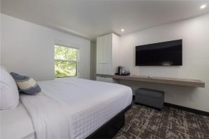 een witte slaapkamer met een bed en een televisie bij Montclair Inn & Suites at Zion National Park in Springdale