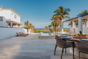 a patio with a table and chairs and the ocean at Villa de lujo frente al mar de Progreso in Progreso