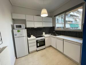 a kitchen with white cabinets and a white refrigerator at Traveller's Choice Attiki in Athens