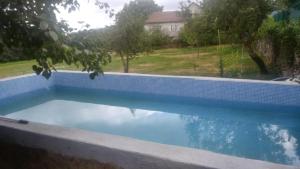 a swimming pool in a backyard with a blue tiled wall at Casa "A Rúa" - Preciosa casa en la montaña con amplio jardín in Vilariño