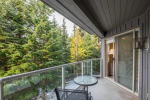 a balcony with a table and chairs and trees at The Aspens by Outpost Whistler in Whistler