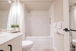 a white bathroom with a toilet and a shower at The Aspens by Outpost Whistler in Whistler