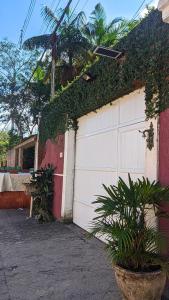 a garage door with ivy on the side of a house at Suite Hanaki com microondas e frigobar in Ubatuba