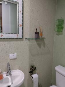 a bathroom with a sink and a mirror and a toilet at Suite Hanaki com microondas e frigobar in Ubatuba