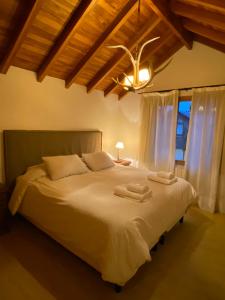 1 dormitorio con 1 cama grande y 2 toallas. en Samay Huasi - 3 dorm en suite - inmejorable ubicación - cochera cub en San Martín de los Andes