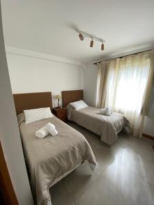 a bedroom with two beds and a window at Samay Huasi - 3 dorm en suite - inmejorable ubicación - cochera cub in San Martín de los Andes