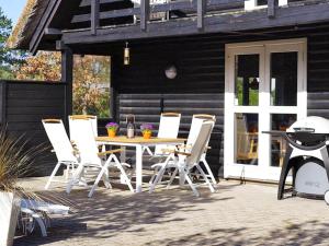 un patio con mesa, sillas y parrilla en 6 person holiday home in R m, en Vesterhede