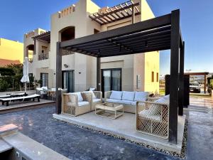 une terrasse avec des canapés et des tables en face d'une maison dans l'établissement Luxurious Villa with Infinity Private Pool & Jacuzzi over Sabina Island's Lagoon, à Hurghada