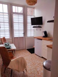 a kitchen with a table and chairs and a kitchen with windows at appartement Rez-de-chaussée avec extérieur, a 150m du centre, 4min de la plage. in Mers-les-Bains