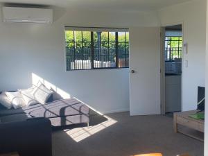 a living room with a couch and a window at Bright Cosy Cottage in Whitianga