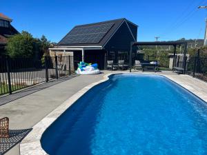 a swimming pool in a backyard with a house at Bright Cosy Cottage in Whitianga