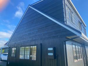 a black house with windows on the side of it at Bright Cosy Cottage in Whitianga
