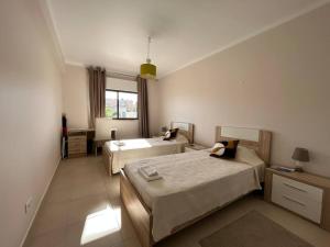 a hotel room with two beds and a window at Falésia Beach Apartment in Albufeira