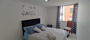 ein Schlafzimmer mit einem Bett mit blauen Kissen in der Unterkunft APARTAMENTO COMODO NORMANDIA in Bogotá