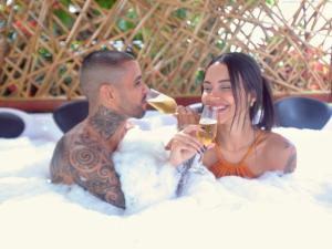 un hombre y una mujer sentados en una bañera bebiendo vino en Pousada do Bispo, en Cabo Frío