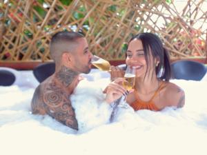 a man and a woman sitting in a bathtub drinking wine at Pousada do Bispo in Cabo Frio