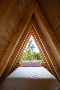 a bed in the attic with a window at Cabañas Chalets Piedra Alta Zacatlan in Camotepec