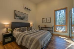 a bedroom with a bed and a table and a window at Malaya Dunes Walk To Laketown Beach in Holland