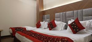 2 Betten in einem Hotelzimmer mit roten und weißen Kissen in der Unterkunft Hotel Batra Home Nizamuddin in Neu-Delhi