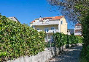 a house behind a hedge in front of a road at Apartments by the sea Kastel Stafilic, Kastela - 21145 in Kaštela