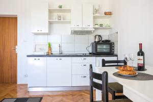 a kitchen with white cabinets and a table with a plate of bread at Apartments by the sea Kastel Stafilic, Kastela - 21145 in Kaštela