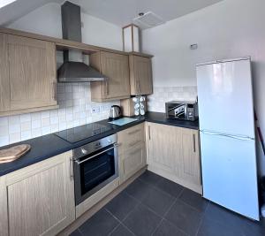 uma cozinha com armários de madeira e um frigorífico branco em Lancaster Heights em Woodhall Spa