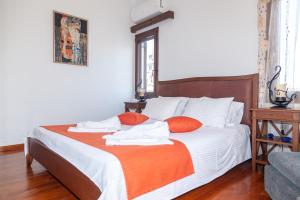 una camera da letto con un letto con lenzuola bianche e cuscini arancioni di Serenita a Chania
