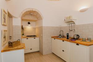 una cucina con armadi bianchi e piano di lavoro di Milestones Modern Suite Trullo Jacuzzi Spa & Relax ad Alberobello