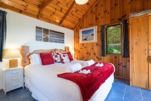 a bedroom with a large bed in a room with wooden walls at Palm Beach - SupaCute Cottage, Sky TV, Wifi and possibly a Car in Palm Beach