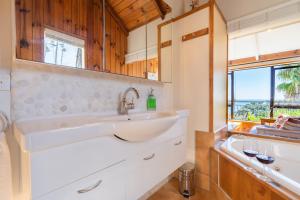 a bathroom with a sink and a tub and a window at Palm Beach - SupaCute Cottage, Sky TV, Wifi and possibly a Car in Palm Beach