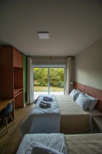 JaguariaívaにあるChakras Pousadaのベッドルーム1室(ベッド2台、大きな窓付)