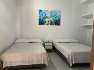 two beds in a room with a painting on the wall at Casa Paraiso del Lago in Prado