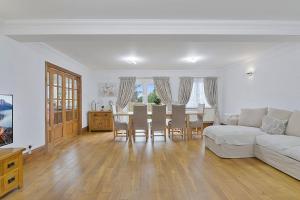 sala de estar con sofá blanco, mesa y sillas en Modern 8-Bed Home - Parking, Wi-Fi, 5 mins to Town, en Gravesend