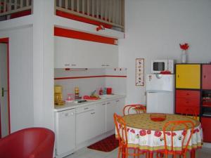 eine Küche mit einem Tisch und einem weißen Kühlschrank in der Unterkunft Maison Les Sables-d'Olonne, 3 pièces, 4 personnes - FR-1-92-677 in Saint-Jean-dʼOrbetiers