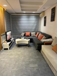 uma sala de estar com um sofá e uma televisão em Résidence Galets Sur Mer em Dar Bouazza