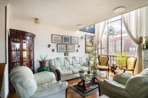 sala de estar con muebles blancos y ventana grande en Habitaciones en un alojamiento -Anfitrion - Elias Di Caprio, en Bogotá