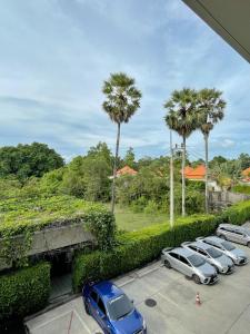 Une rangée de voitures garées dans un parking avec des palmiers dans l'établissement Diamond Resort by I Am Home, à Bang Tao Beach