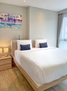 una camera da letto con un grande letto con lenzuola bianche e cuscini blu di Diamond Resort by I Am Home a Bang Tao Beach